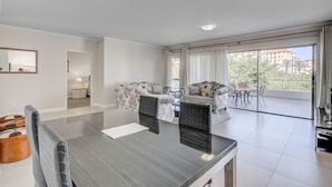 Sala de estar moderna com área de jantar, conjunto de sofás e varanda com vista.