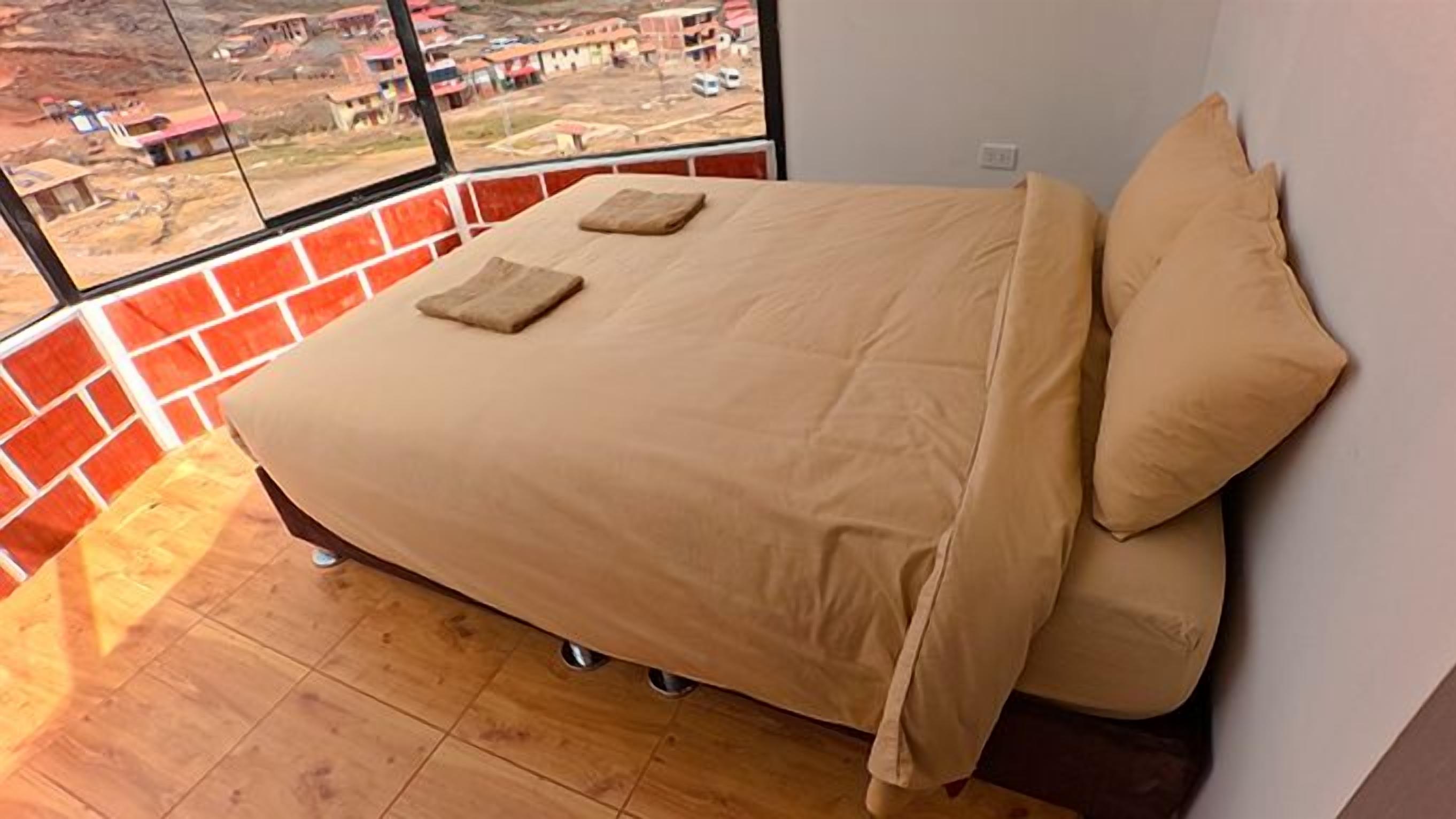 Una cama con vista a una pared de ladrillo y una ventana.