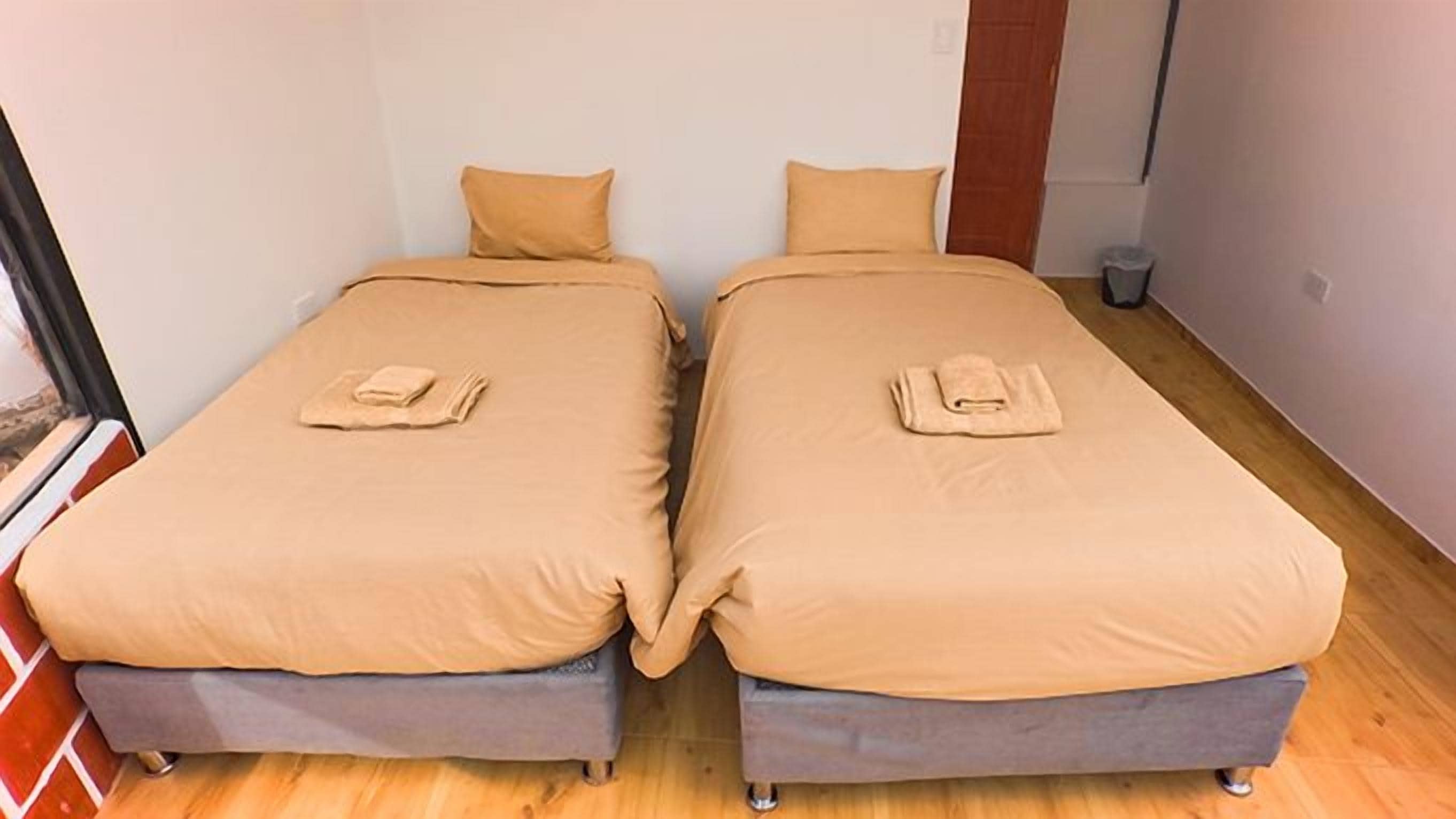 Two single beds with matching headboards and footboards, each with a folded towel on the bed.