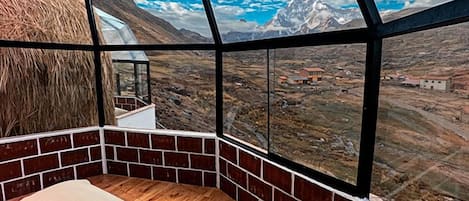 A room with a large window offering a view of a mountainous landscape.