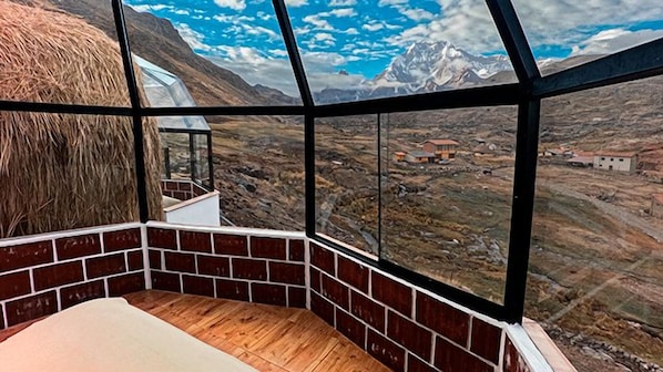 A room with a large window offering a view of a mountainous landscape.