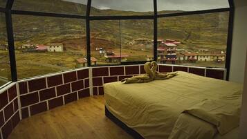 A room with a large window, a bed, and a teddy bear.