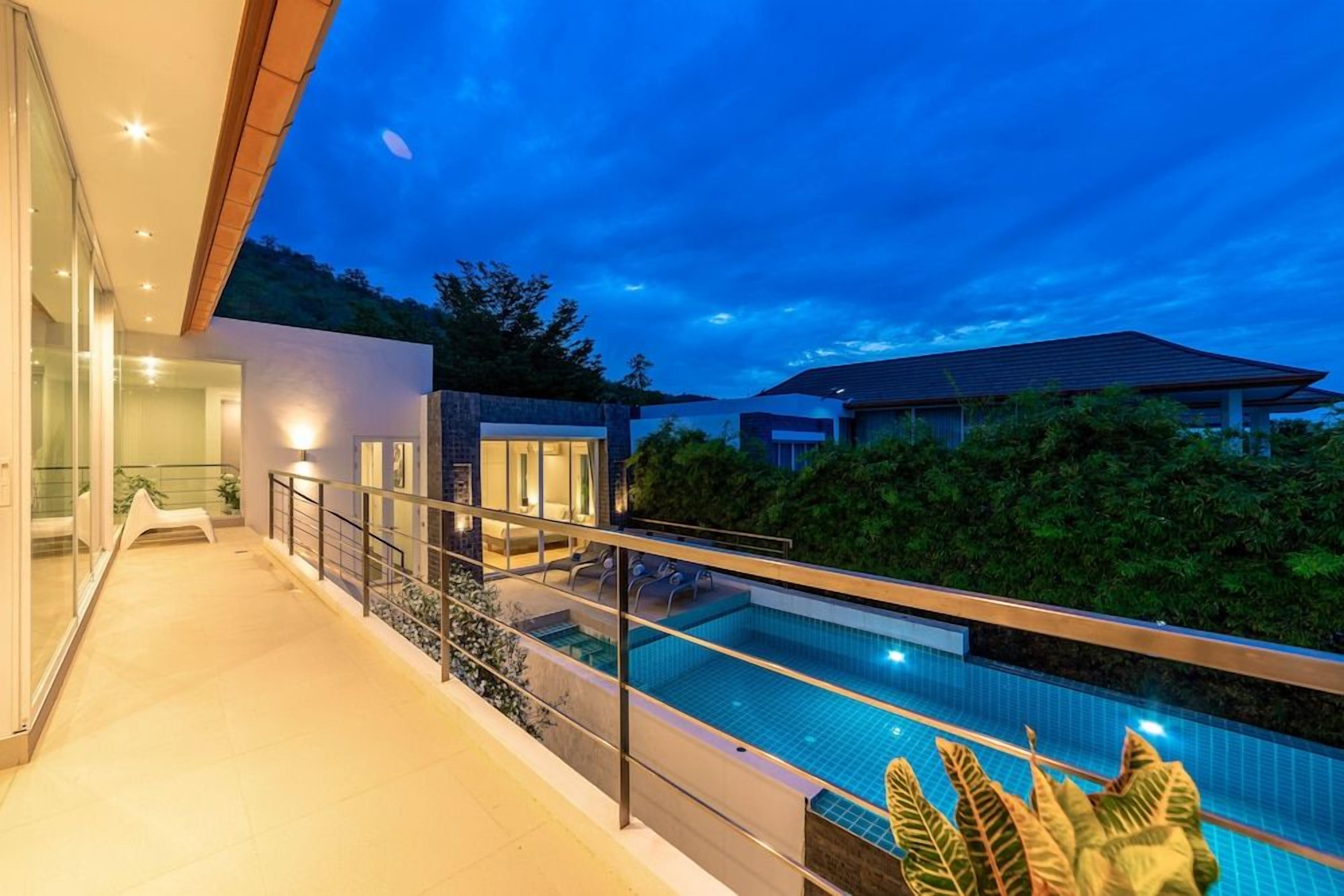 Ein modernes Wohnhaus mit Schwimmbad, Glasfenstern und einem Balkon.