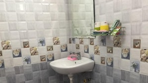 A bathroom with a white sink, tiled walls, and a mirror. - Mai Apartment (Da Nang Municipality)