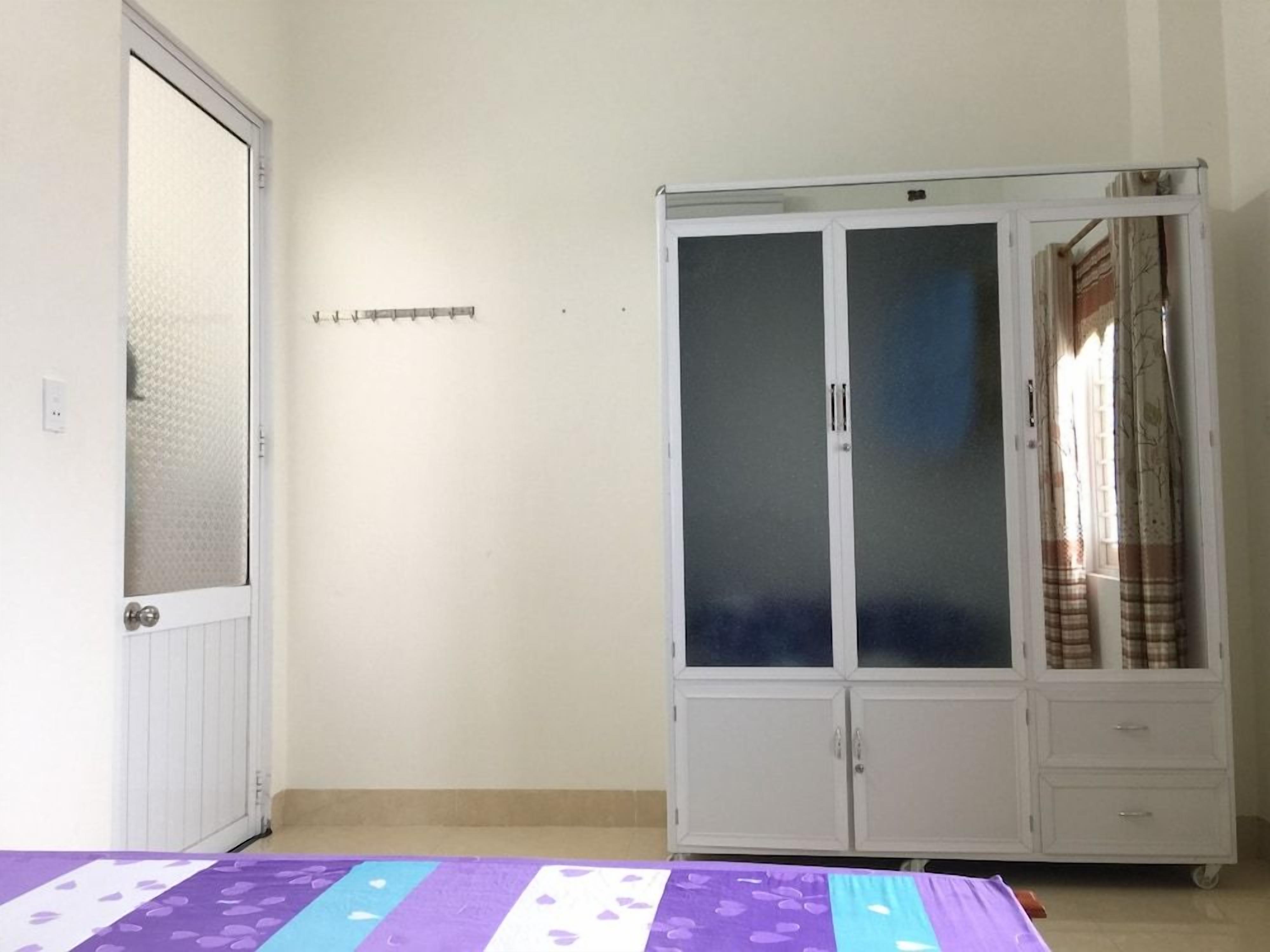 A room with a bed, a wardrobe, and a door.
