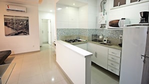 Una cocina moderna con armarios blancos, una estufa a gas, un microondas y un refrigerador.