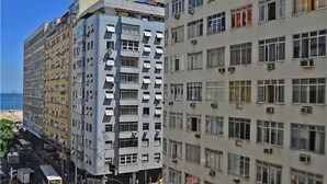 Un edificio de varios pisos con balcones, una zona peatonal y vista despejada al mar.