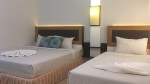 Une chambre d’hôtel avec deux lits, chacun doté d’une tête de lit, d’une table de chevet et d’une lampe placée entre les lits.