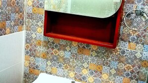 A bathroom with a white sink, a red medicine cabinet, and a patterned tile backsplash. - Ambrosial Suites (Pattaya)