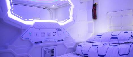 Ein Zimmer mit einem Bett, einer Bedienkonsole und einem an der Wand befestigten Feuerlöscher.