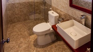 A bathroom with a glass-enclosed shower, a toilet, and a sink with a mirror. - Gia Phát (Da Nang Municipality)