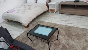 A bedroom with a bed, bedside tables, a small table, and a sofa. - Studio Arcade (Abidjan)