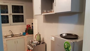 A compact kitchen with a refrigerator, stove, sink, and cabinets. - Résidence Petite Villa (Abidjan)