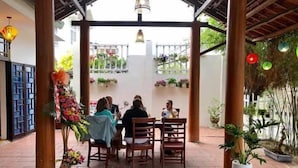 An outdoor patio with a covered seating area, potted plants, and hanging decorations. - Tri Tran Homestay (Da Nang Municipality)