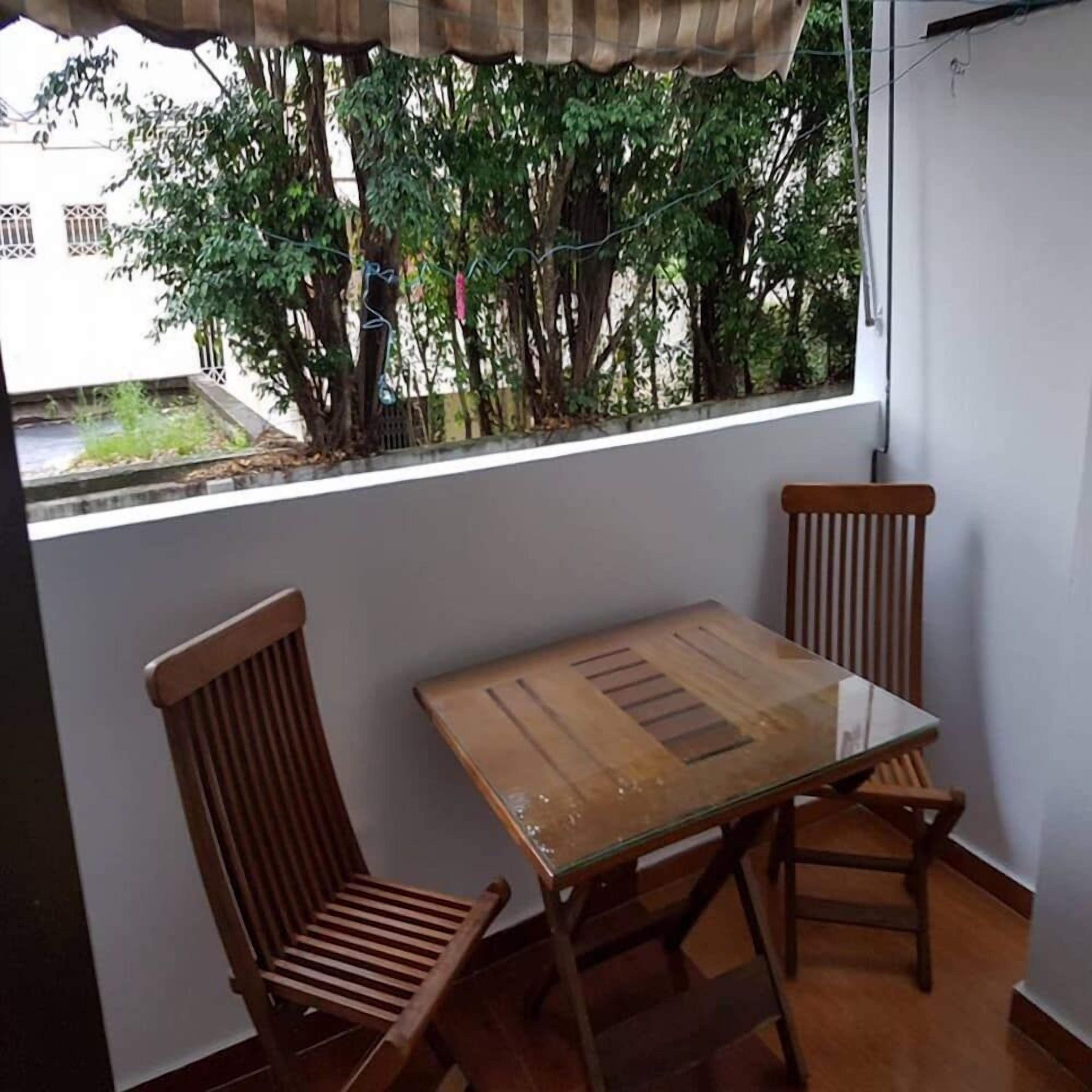 Un balcón con una mesa de vidrio y dos sillas de madera.