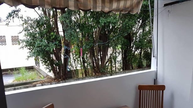 Un balcón con una mesa de vidrio y dos sillas de madera.