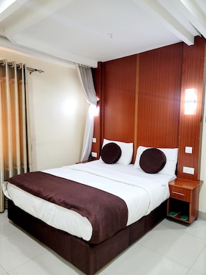 A hotel room with a large bed, wooden headboard, curtains, and a bedside table with a lamp. - Nairobi Glory Palace Hotel Ltd (Nairobi)