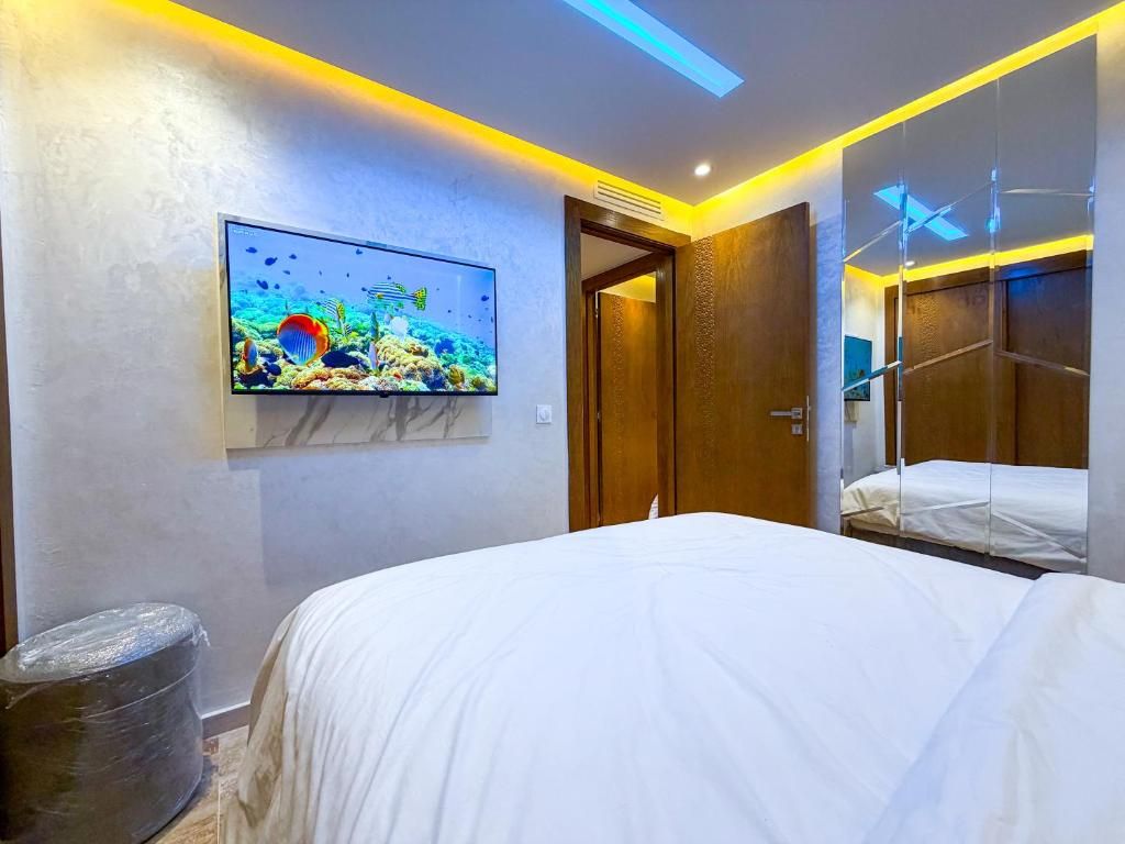 A hotel room with a bed, a television mounted on the wall, and a door leading to another room.