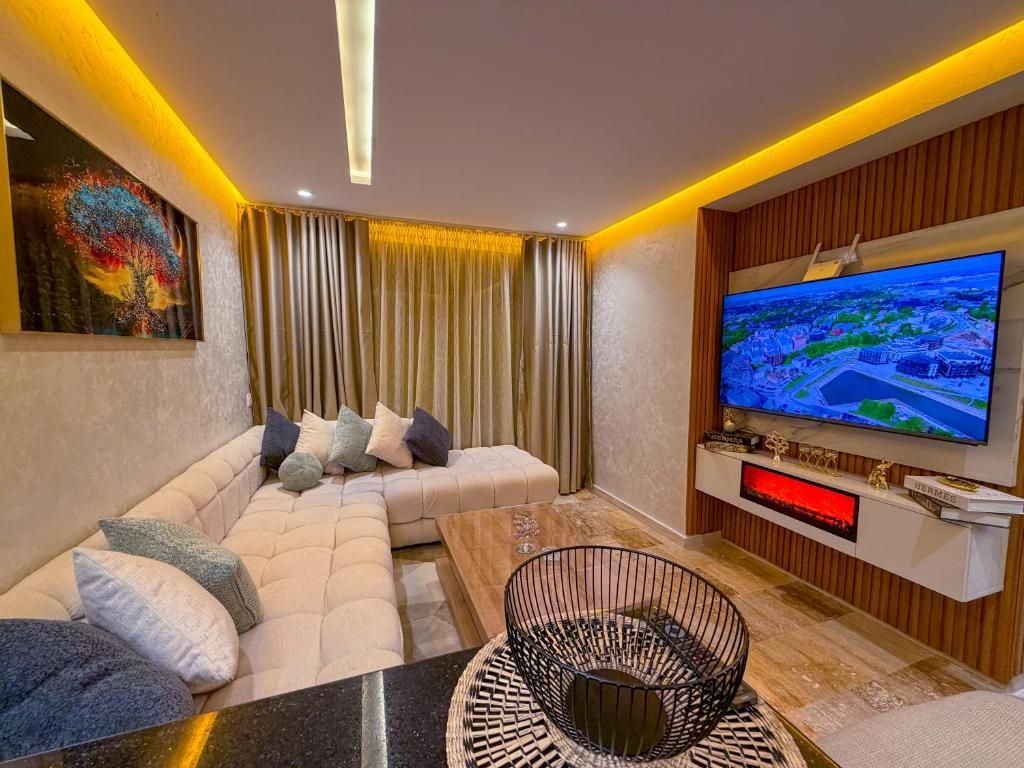 Uma sala de estar moderna com sofá seccional, TV de tela plana e painel decorativo.