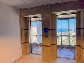 Ein Aufzug mit digitaler Anzeige und Blick auf eine Stadtkulisse durch die Glastüren.