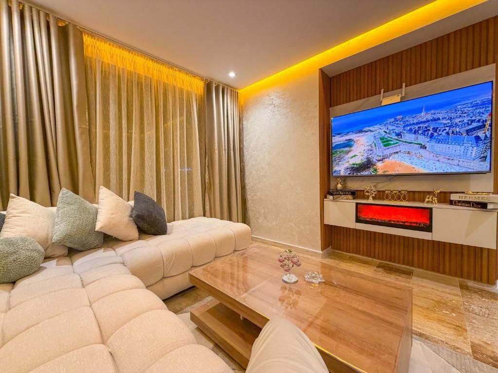 Un salon moderne doté d’un grand téléviseur à écran plat, d’un canapé d’angle et d’une table basse en bois.