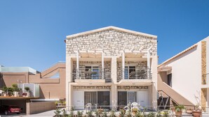 A two-story building with a stone facade, balconies, and a covered outdoor seating area. - Athina Apartments (Platanias)
