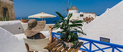 A person relaxing on a chair with a view of a white building and blue sky.