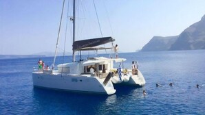 Uno yacht bianco con un ponte coperto e una cabina, che naviga in un mare calmo con una costa montuosa sullo sfondo.