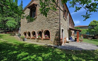 Un edificio de piedra con un porche cubierto y un pequeño jardín.