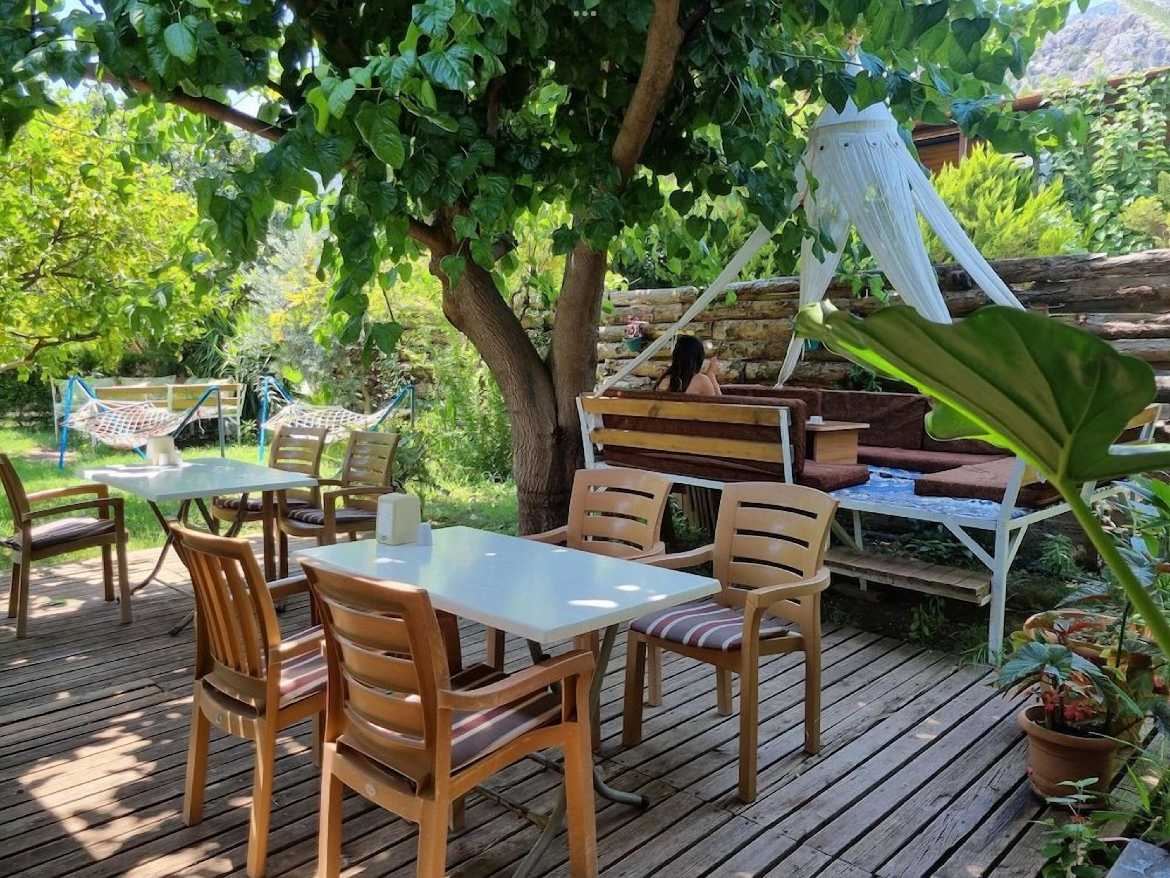An outdoor deck with wooden furniture and a hammock.