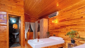 A wooden cabin room with a bed, a small table, a potted plant, and a bathroom with a toilet and sink. - Bungalowsky (Kemer)