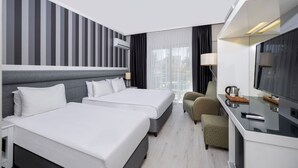 A hotel room with two beds, a desk, a TV, and a window with curtains. - Dedeman Kemer Resort (Kemer)
