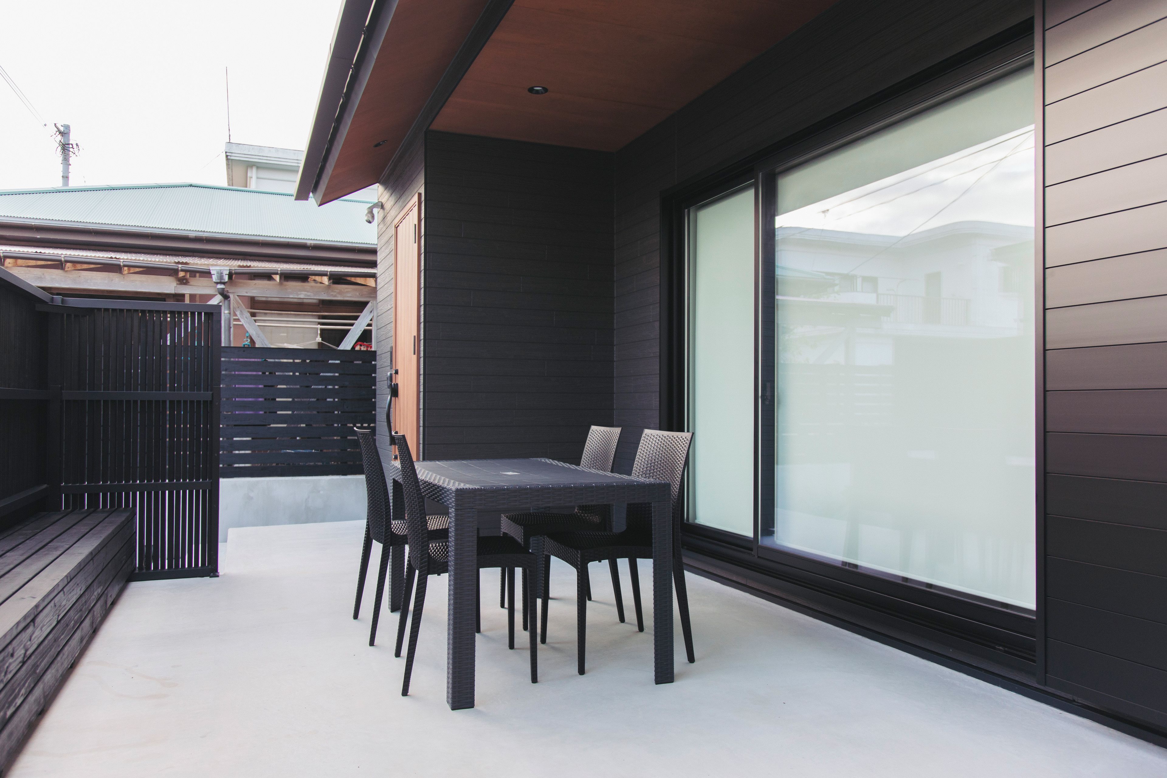 A modern outdoor patio with a dining table and chairs.