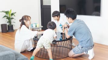 Eine Familie interagiert in einem modernen Wohnzimmer mit einem runden schwarzen Couchtisch, einem Blumentopf und einem großen Fenster.