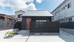 Un edificio residencial moderno con techo de metal, puerta de madera y cerca negra.