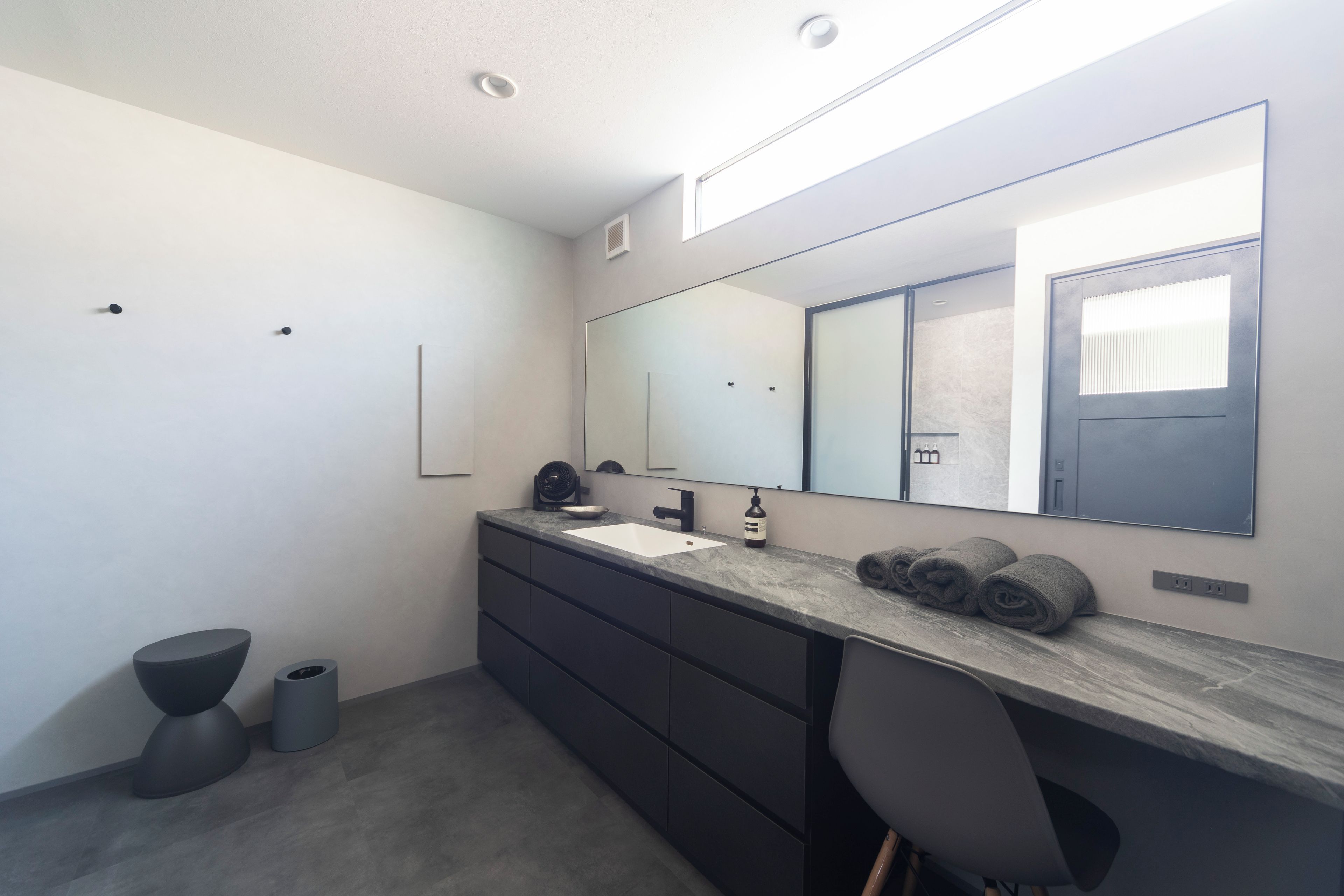 Un baño moderno con un espejo grande, un lavabo y un inodoro.