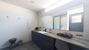 Un baño moderno con un espejo grande, un lavamanos y un inodoro.
