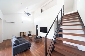 Un salon moderne avec un canapé gris, une table basse ronde et un escalier en bois.