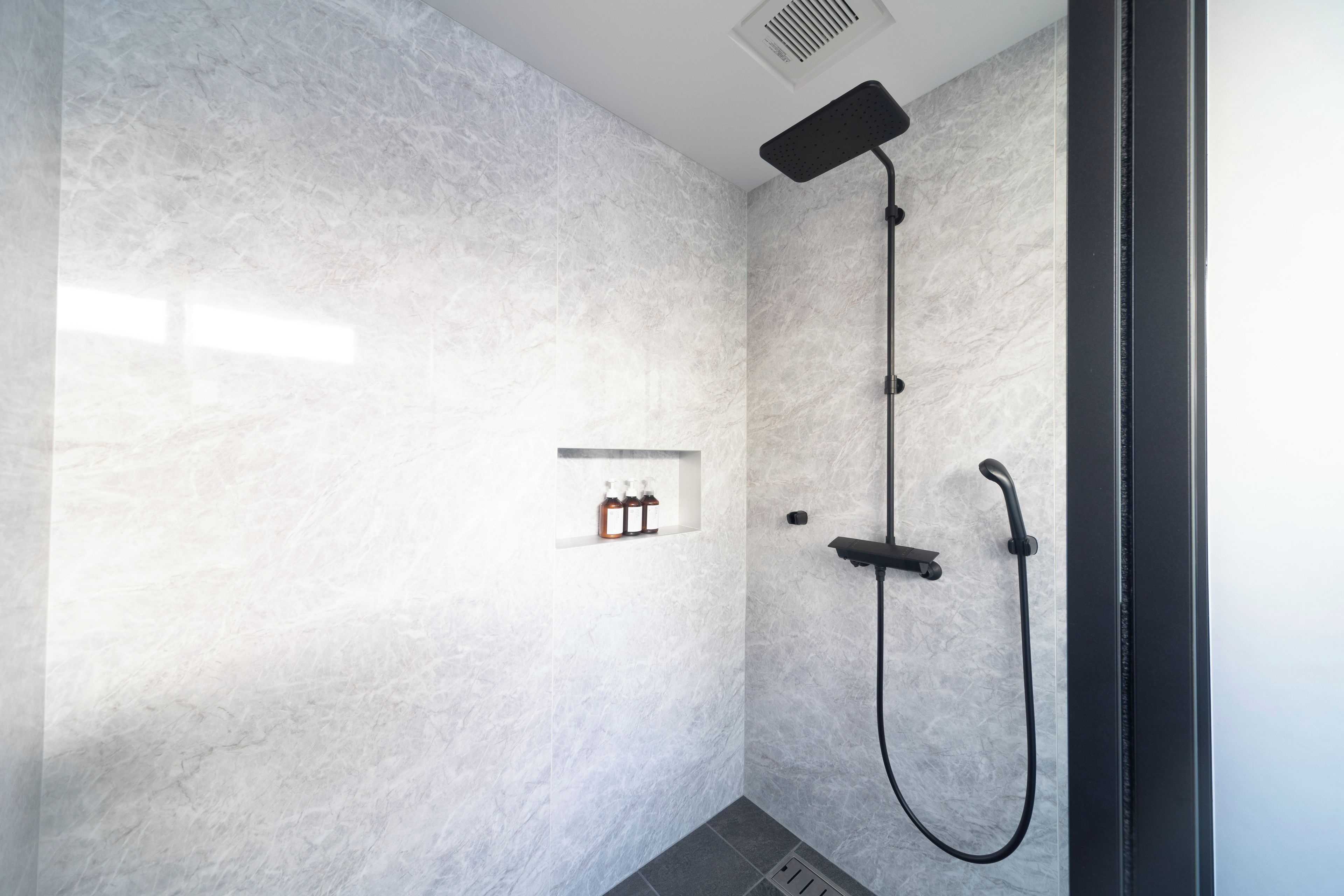 A modern shower with a handheld showerhead and a wall-mounted control panel.
