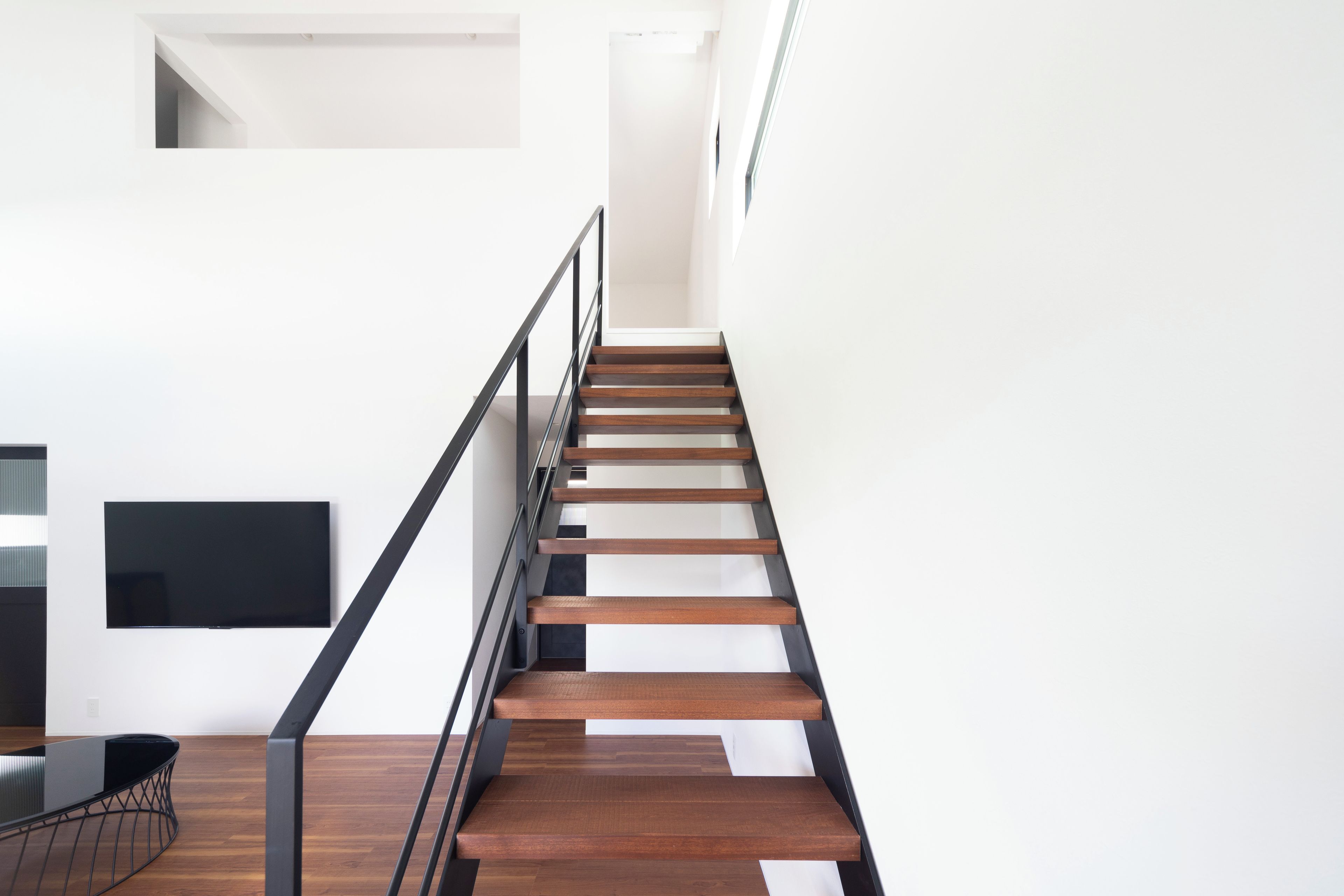 Un escalier moderne avec des marches en bois et des rampes noires.