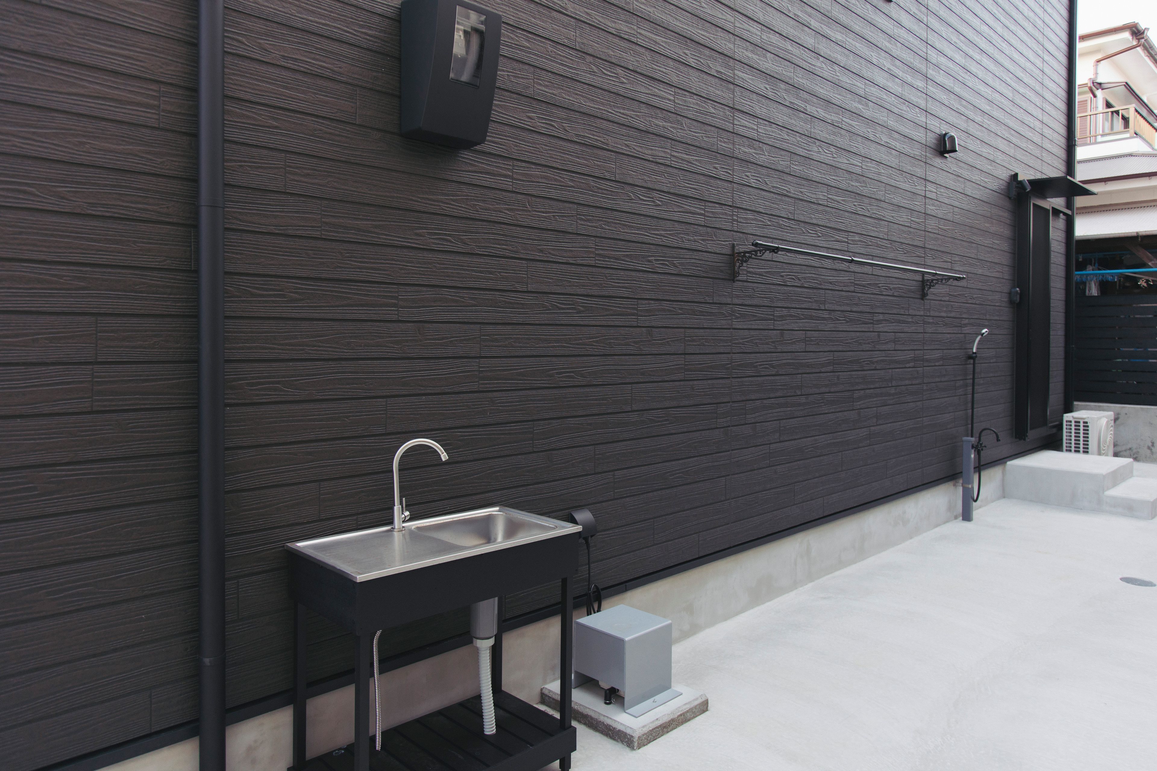 A modern outdoor kitchen with a stainless steel sink and faucet, a built-in heater, and a metal railing.