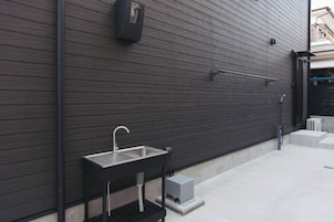 Cocina exterior moderna con un lavamanos y grifo de acero inoxidable, calentador empotrado y baranda metálica.