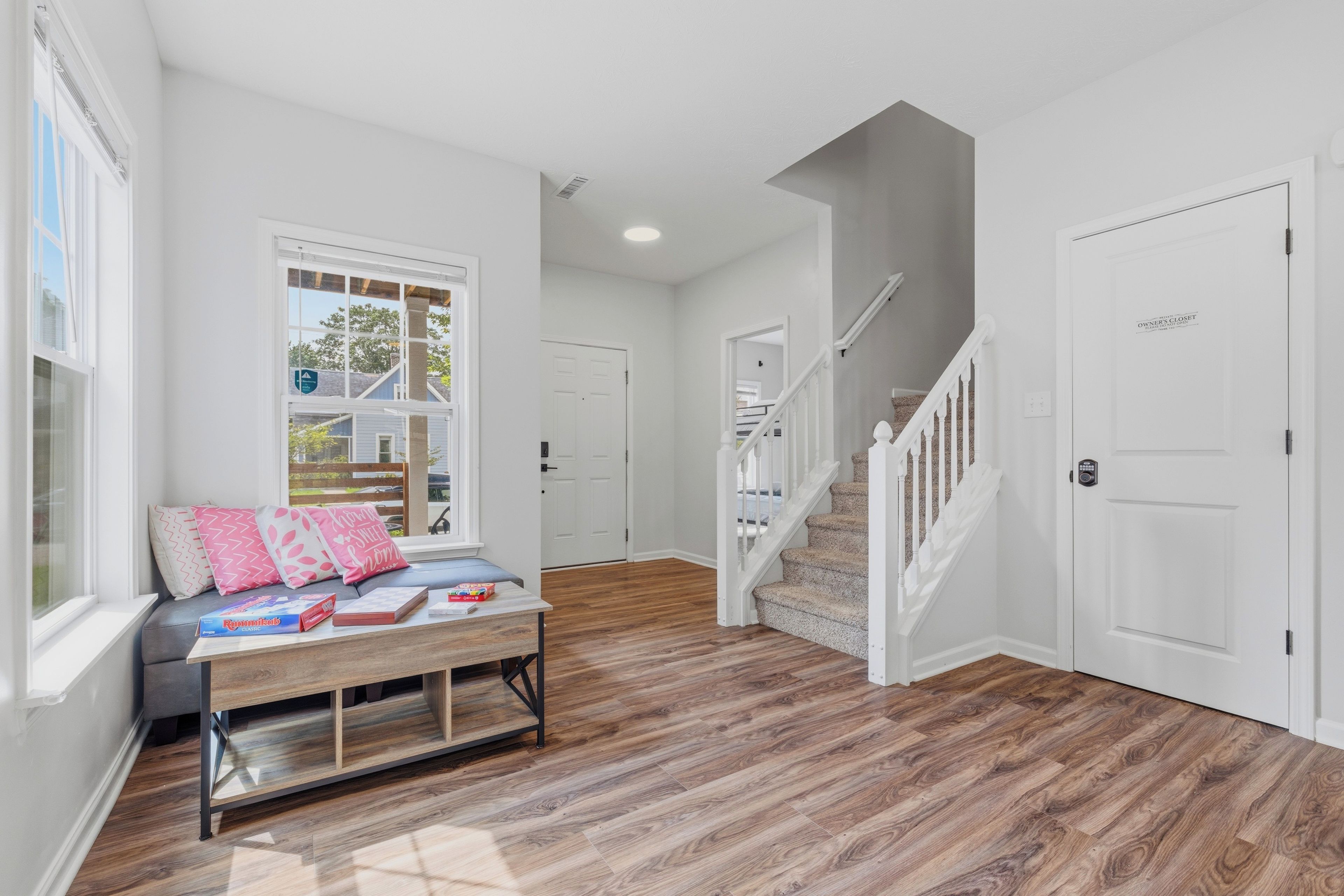 A hallway with a bench, a staircase, and a door.