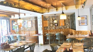 A restaurant interior with wooden ceiling beams, stone walls, and multiple dining tables and chairs. - Treebo Lakeside Inn (Nainital)