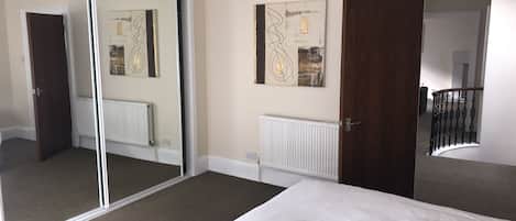 Ein Hotelzimmer mit einem Bett, einem großen Spiegel, einer Heizung und einer Tür, die auf einen Balkon führt.