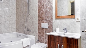 Un baño con bañera, ducha, lavamanos y espejo.