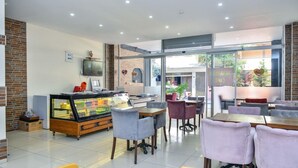 Una cafetería moderna con un expositor de vidrio, zona de estar y vistas al exterior.