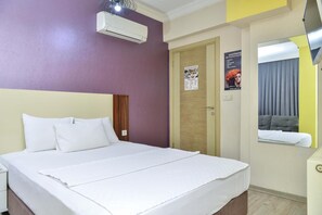 A hotel room with a large bed, an air conditioning unit, a door with a poster, and a mirror reflecting part of the room. - Su Residence Apart Hotel (Izmir)