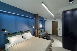 A modern hotel room with a bed, a sofa, a small table, and a door. - Sir Athens (Athens)