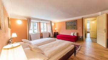 A hotel room with a large bed, a red sofa, a painting on the wall, and a view of the outside.